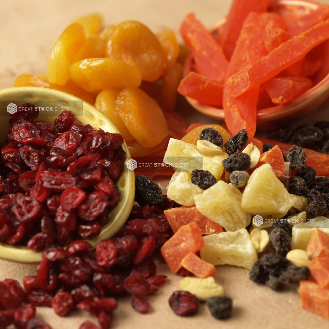 Close Up of Assorted Dried and Candied Fruits - Cranberries, Raisins, Pineapples, Papaya, Apricots - in an Indoor Setting