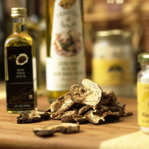 Dried Porcini Mushroom Slices on a Wooden Cutting Board with Assorted Gourmet Oils in an Indoor Setting