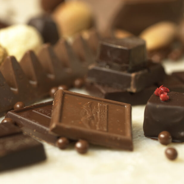 Close Up of Milk and Dark Chocolate Ghirardelli Squares Surrounded by Other Chocolates in an Indoor Setting