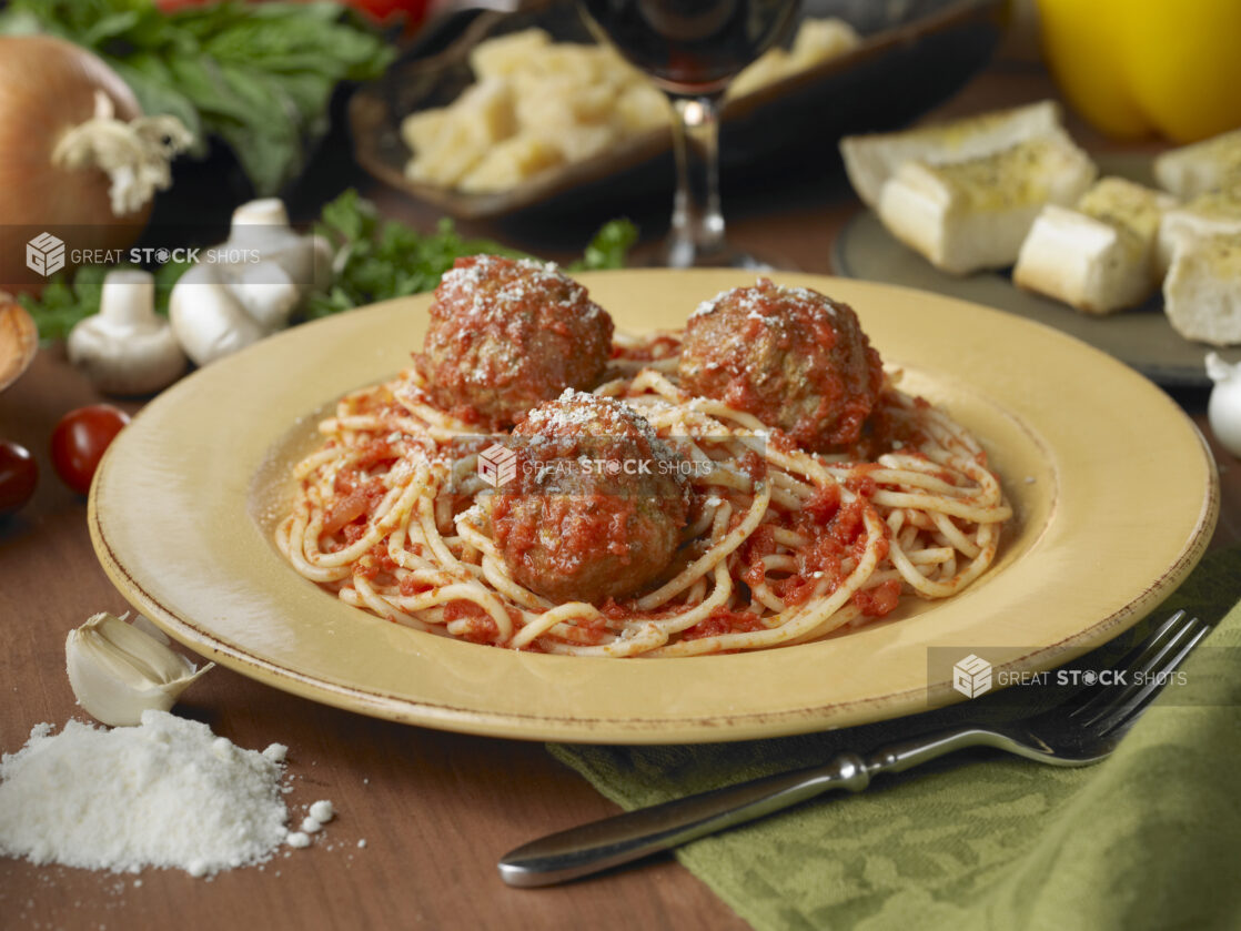 Spaghetti and Meatballs in a Yellow Ceramic Dish on a Wooden Table in an Indoor Setting