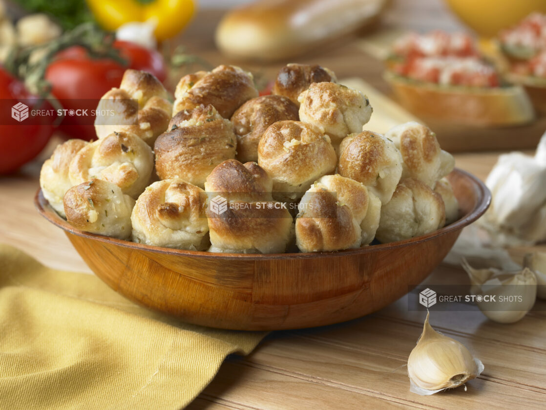 A Wooden Bowl of Garlic Knots on a Wooden Table in a Kitchen Setting