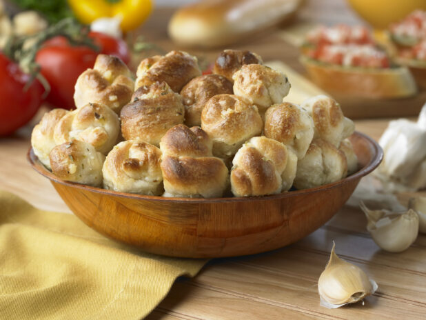 A Wooden Bowl of Garlic Knots on a Wooden Table in a Kitchen Setting