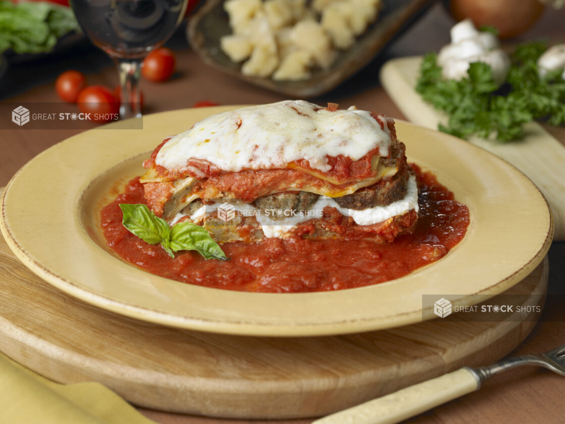 Baked Lasagna with Ricotta Cheese and Sliced Meatballs on a Bed of Marinara Sauce in a Yellow Ceramic Dish in a Kitchen Setting