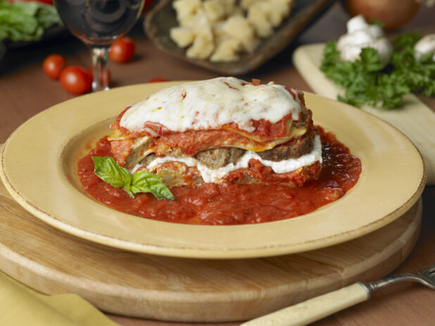 Baked Lasagna with Ricotta Cheese and Sliced Meatballs on a Bed of Marinara Sauce in a Yellow Ceramic Dish in a Kitchen Setting