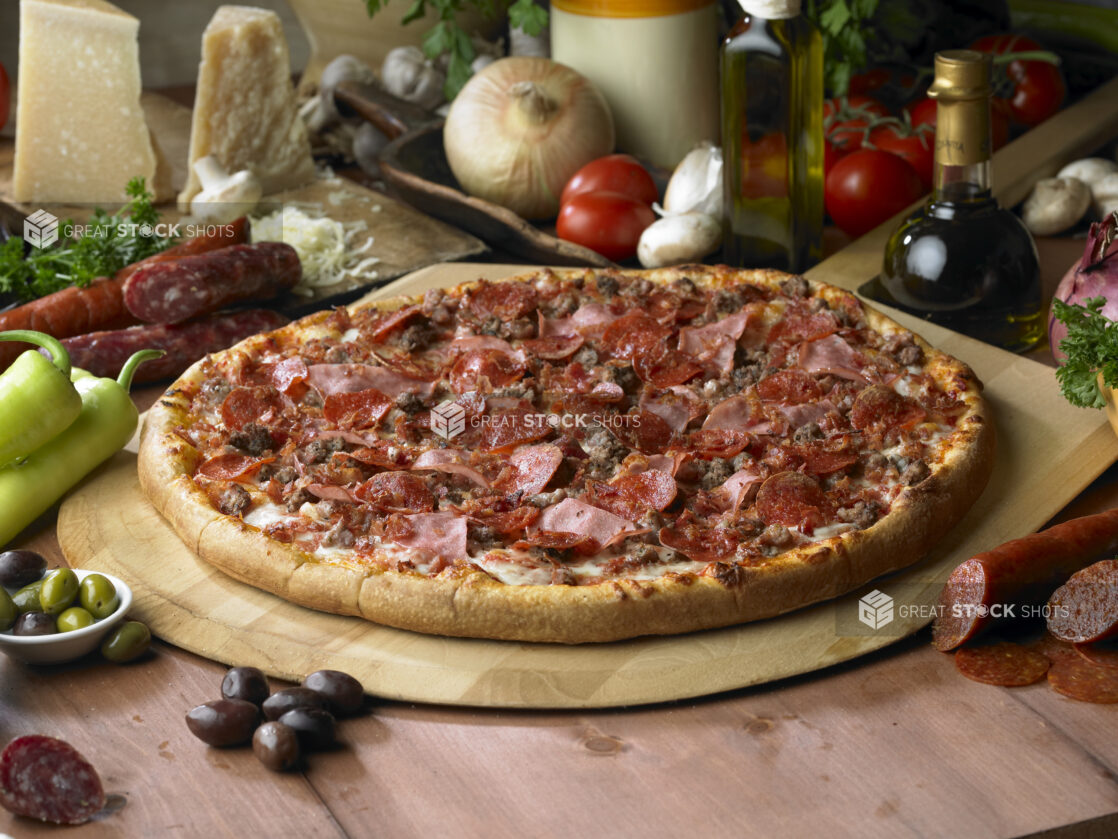 Whole Meat Lovers Pizza with Sliced Ham, Pepperoni, Bacon and Ground Beef on a Wooden Pizza Peel in a Indoor Setting