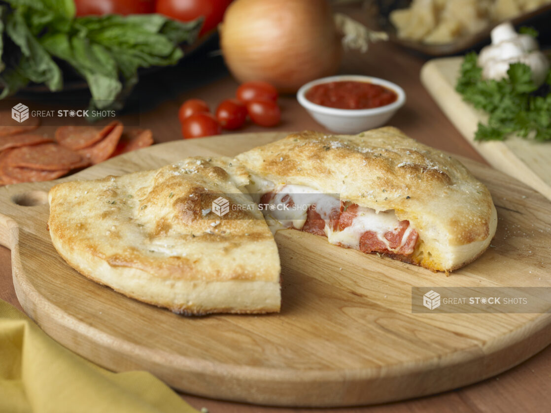 A Pepperoni and Cheese Calzone Cut in Half on a Wooden Cutting Board in a Kitchen Setting