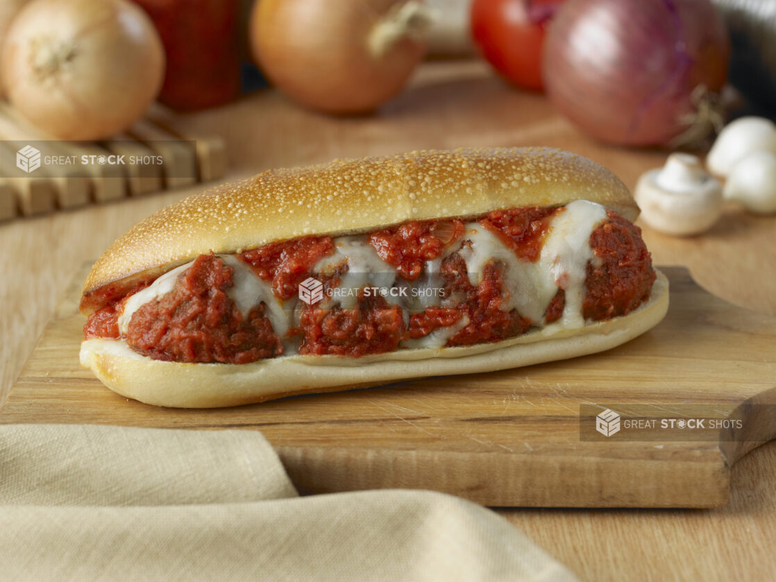 Hot Toasted Meatball Sub Sandwich with Melted Mozzarella Cheese on a Wooden Cutting Board in an Indoor Setting