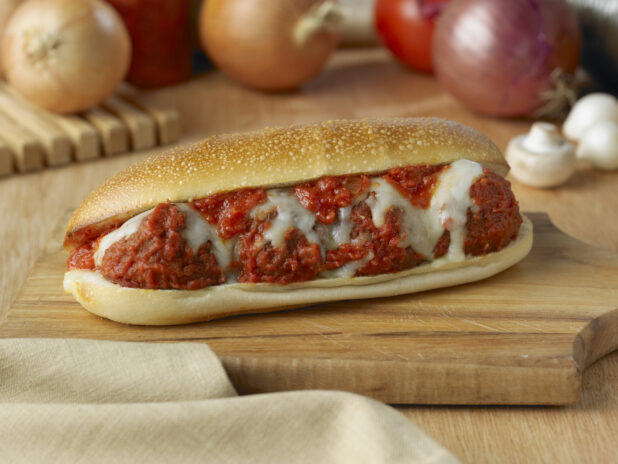 Hot Toasted Meatball Sub Sandwich with Melted Mozzarella Cheese on a Wooden Cutting Board in an Indoor Setting