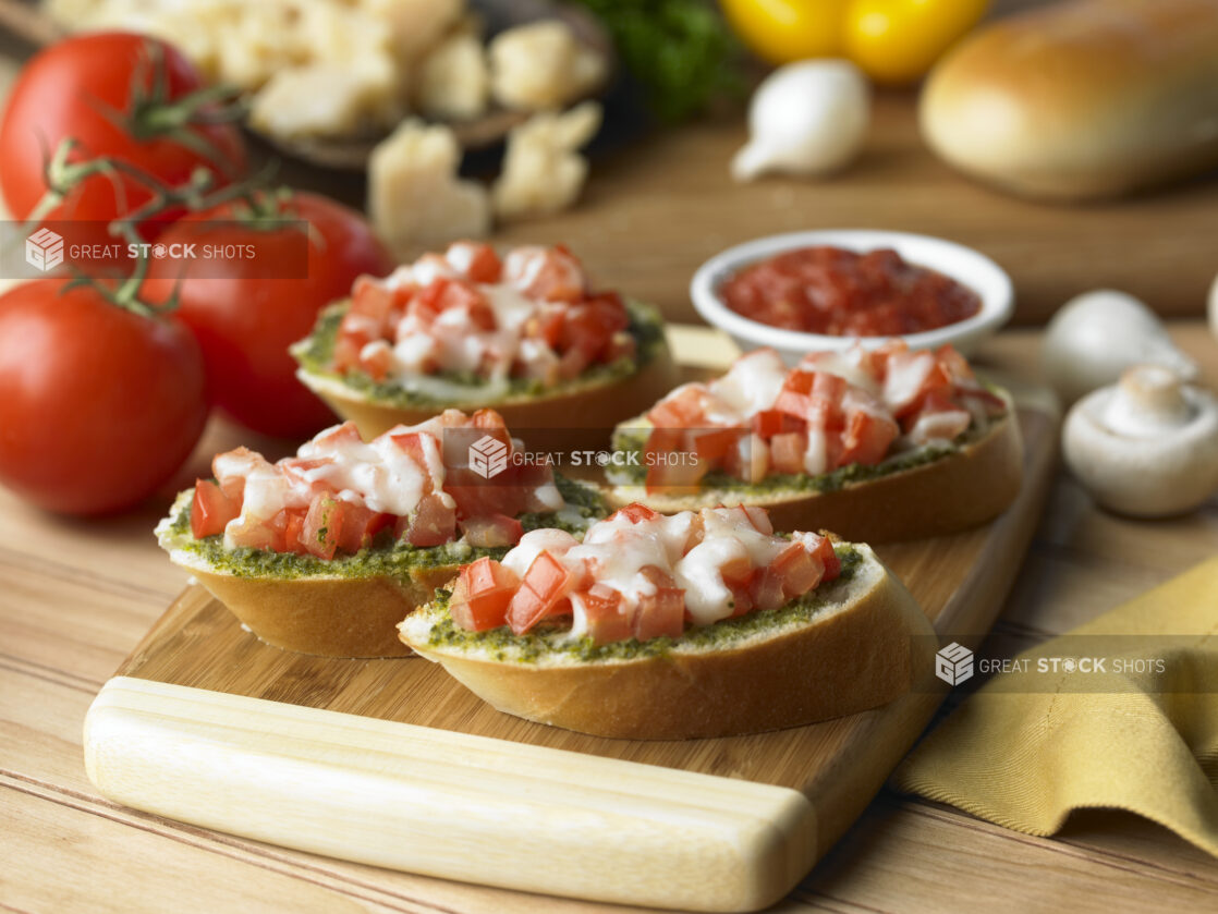 Tomato Pesto Bruschetta on Sliced Italian Bread on a Wooden Cutting Board in a Kitchen Setting - Variation