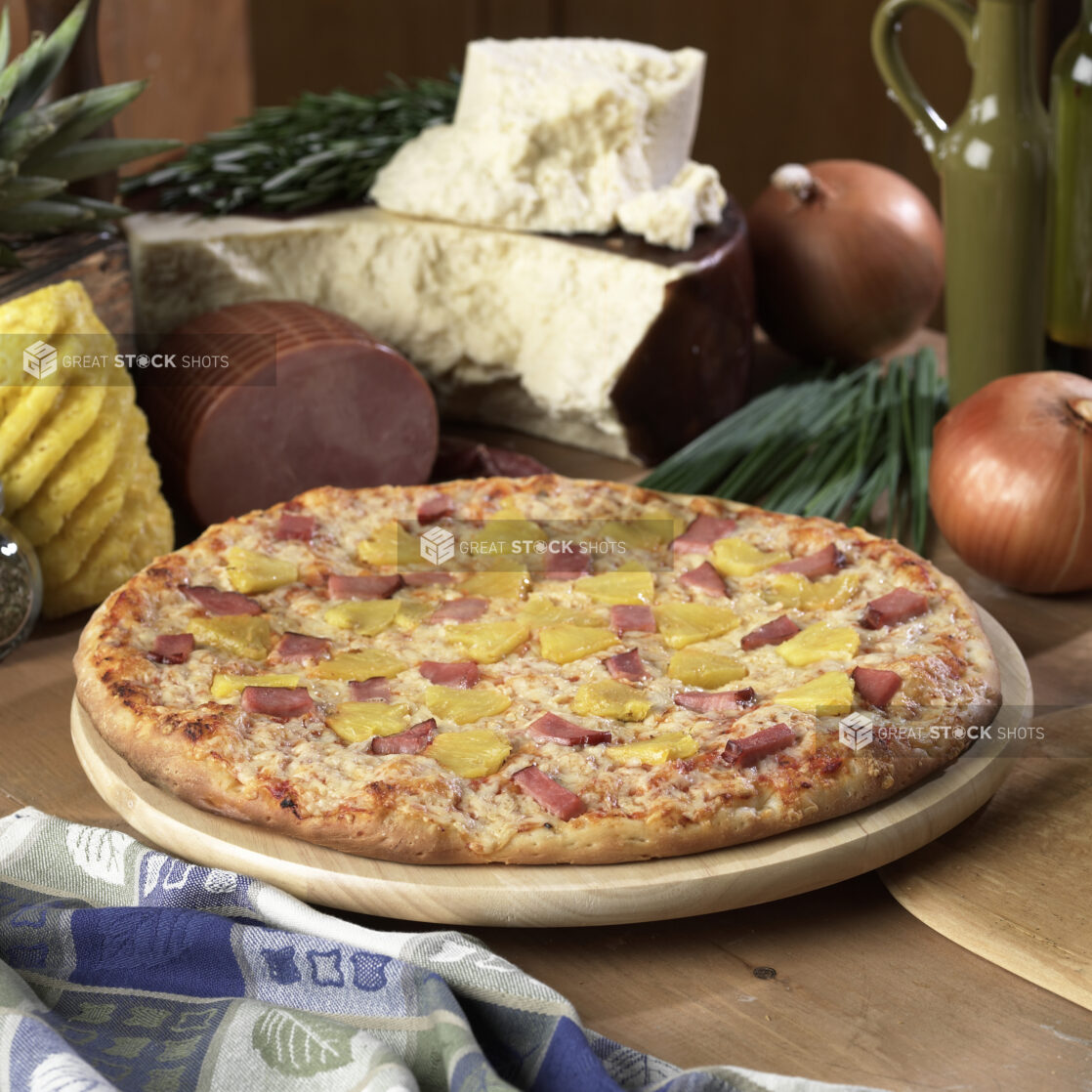 Whole Hawaiian Pizza with Sliced Ham and Pineapple Toppings on a Wooden Pizza Platter on a Wooden Table in an Indoor Setting