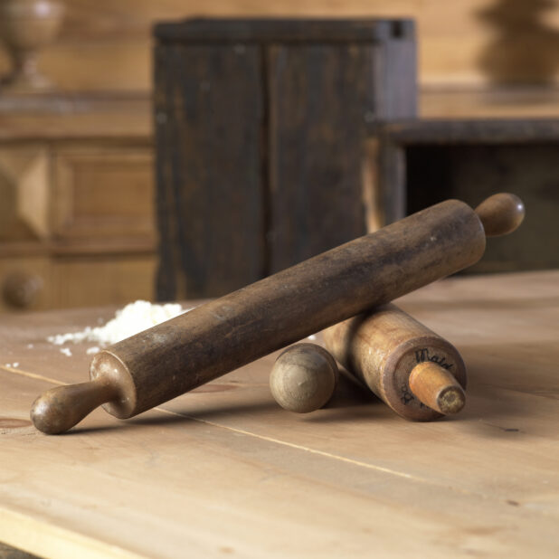 An Assortment of Well Used Rolling Pins on a Wooden Table in a Kitchen Setting