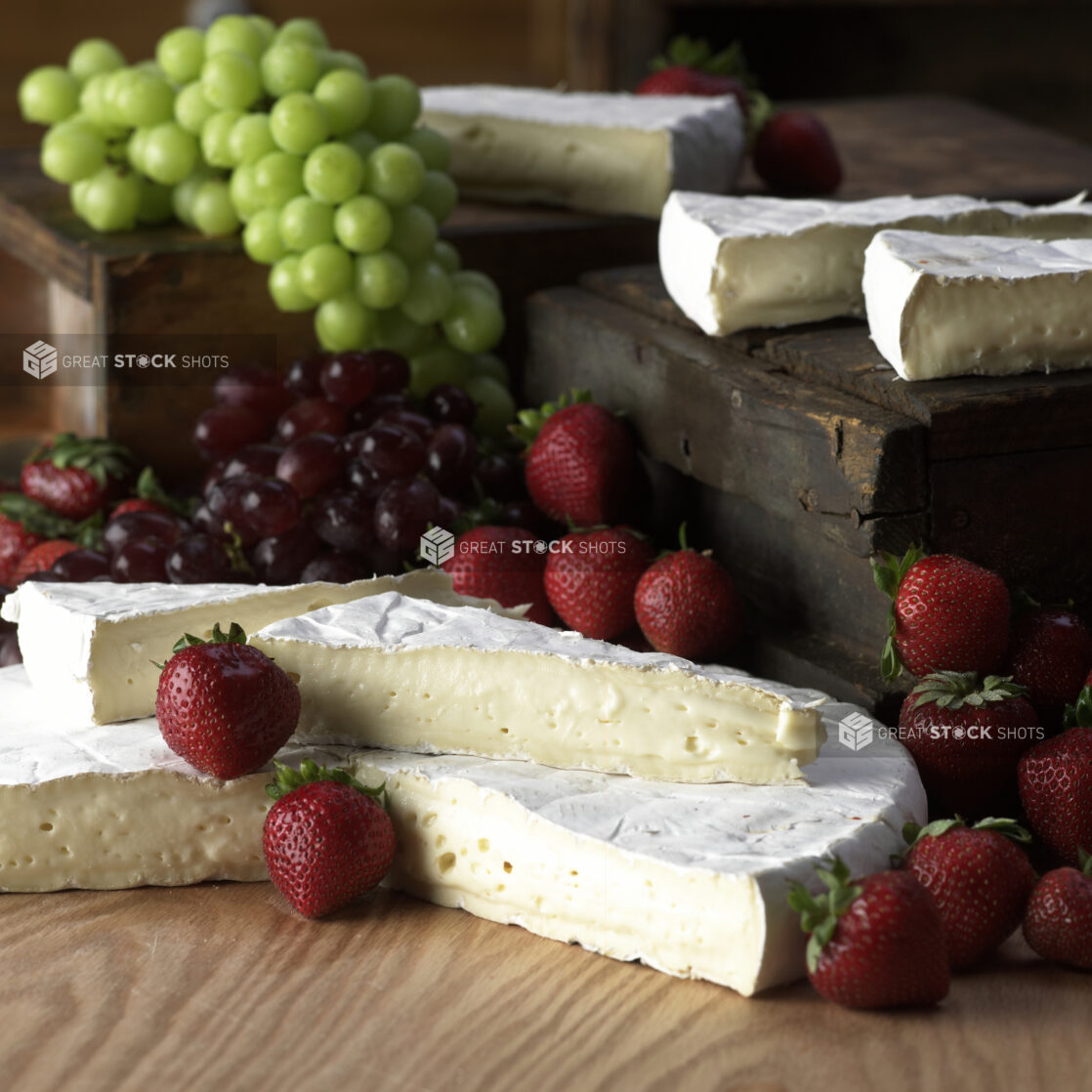 Wedges of Creamy Brie Cheese with Fresh Strawberries and Grapes on a Wooden Table in a Kitchen Setting - Variation