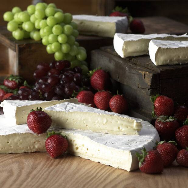 Wedges of Creamy Brie Cheese with Fresh Strawberries and Grapes on a Wooden Table in a Kitchen Setting - Variation
