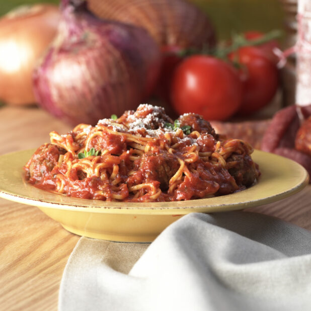 Spaghetti and Meatballs in Marinara Sauce in a Yellow Ceramic Bowl on a Wooden Table