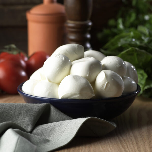 A Bowl of Fresh Buffalo Mozzarella Balls on a Wooden Surface in an Indoor Setting