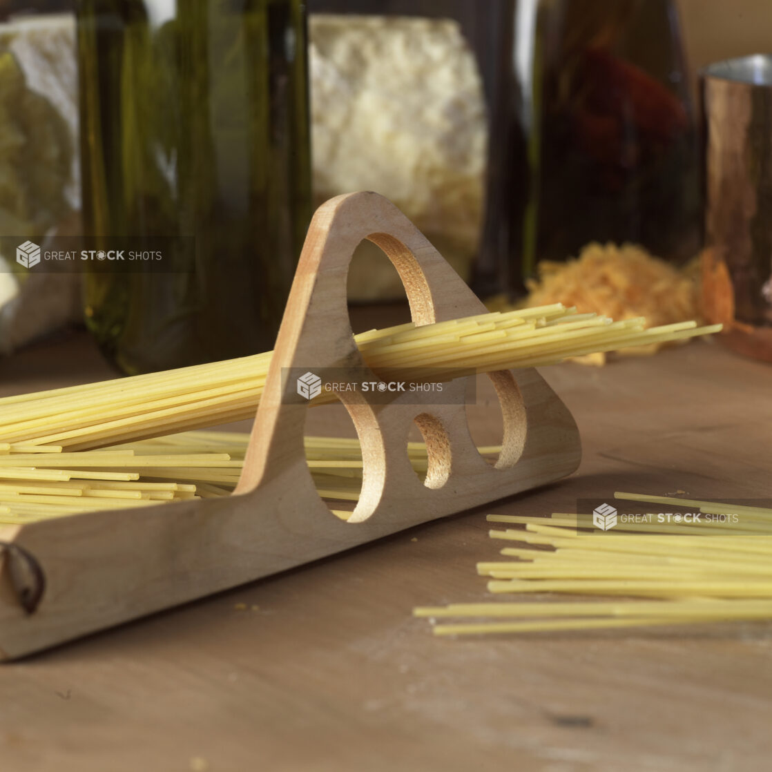 Dry Spaghetti Noodles in a Wooden Pasta Portion Measuring Tool on a Wooden Cutting Board in a Kitchen Setting