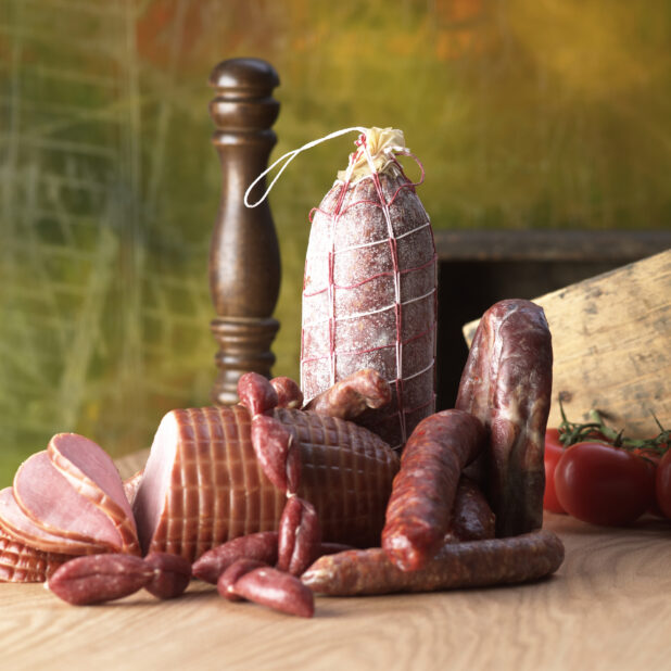 An Array of Whole Cured Deli Meats on a Wooden Table in an Indoor Setting