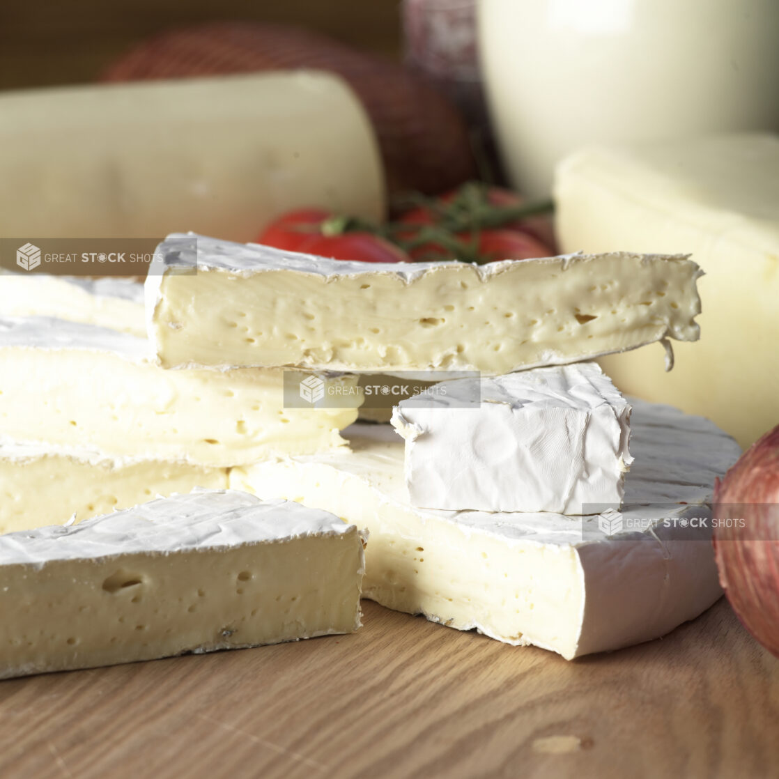 Wedges of Creamy Brie Cheese Stacked on a Wooden Table in a Kitchen Setting