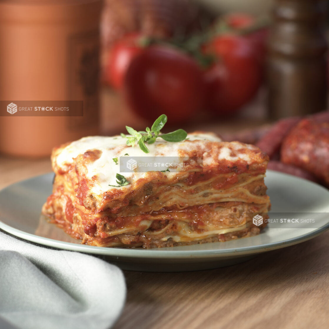 Thick Stacked Meat Lasagna on a Grey Ceramic Dish on a Wooden Table in an Indoor Setting