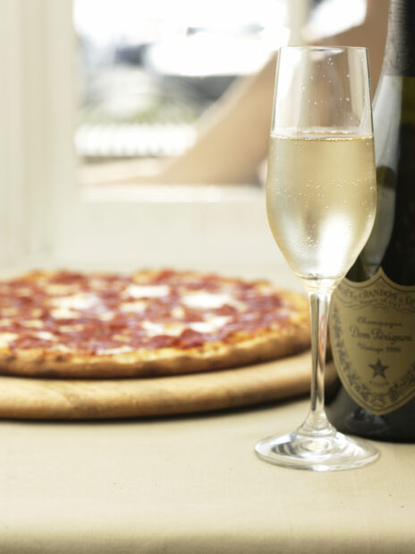 A Champagne Glass Flute of Dom Pérignon Vintage Champagne with a Pepperoni Pizza in a Restaurant Setting