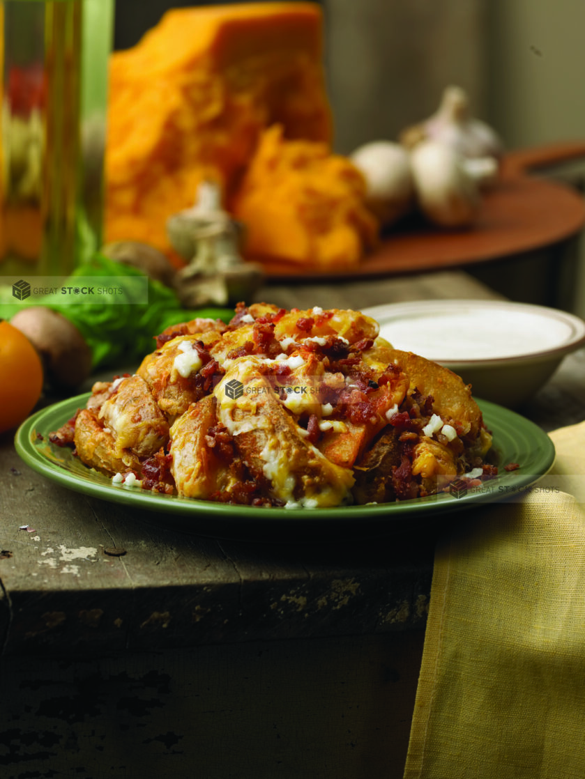 Bacon Cheddar Potato Wedges on a Dark Green Ceramic Dish on a Rustic Wooden Table in an Indoor Setting