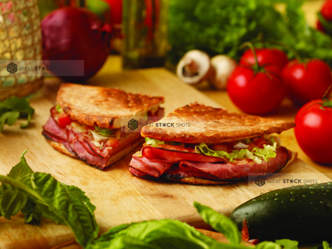 Deli Sandwiches Made with Pizza Crusts on a Wooden Cutting Board in an Indoor Setting