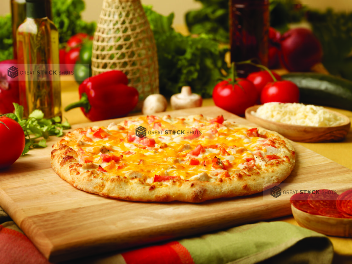 Chicken, Tomato and Cheddar Pizza on a Wooden Cutting Board in an Indoor Setting