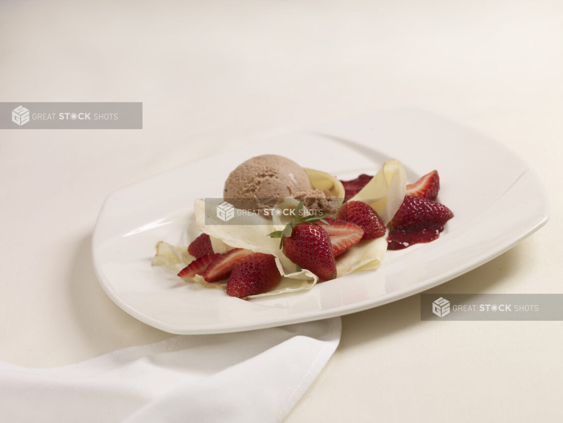A Dessert Made of Crepe, Fresh Strawberries and Chocolate Ice Cream on a White Ceramic Dish