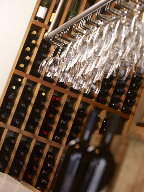 A Restaurant Wine Rack with Bottles of Red Wine and Hanging Wine Glasses