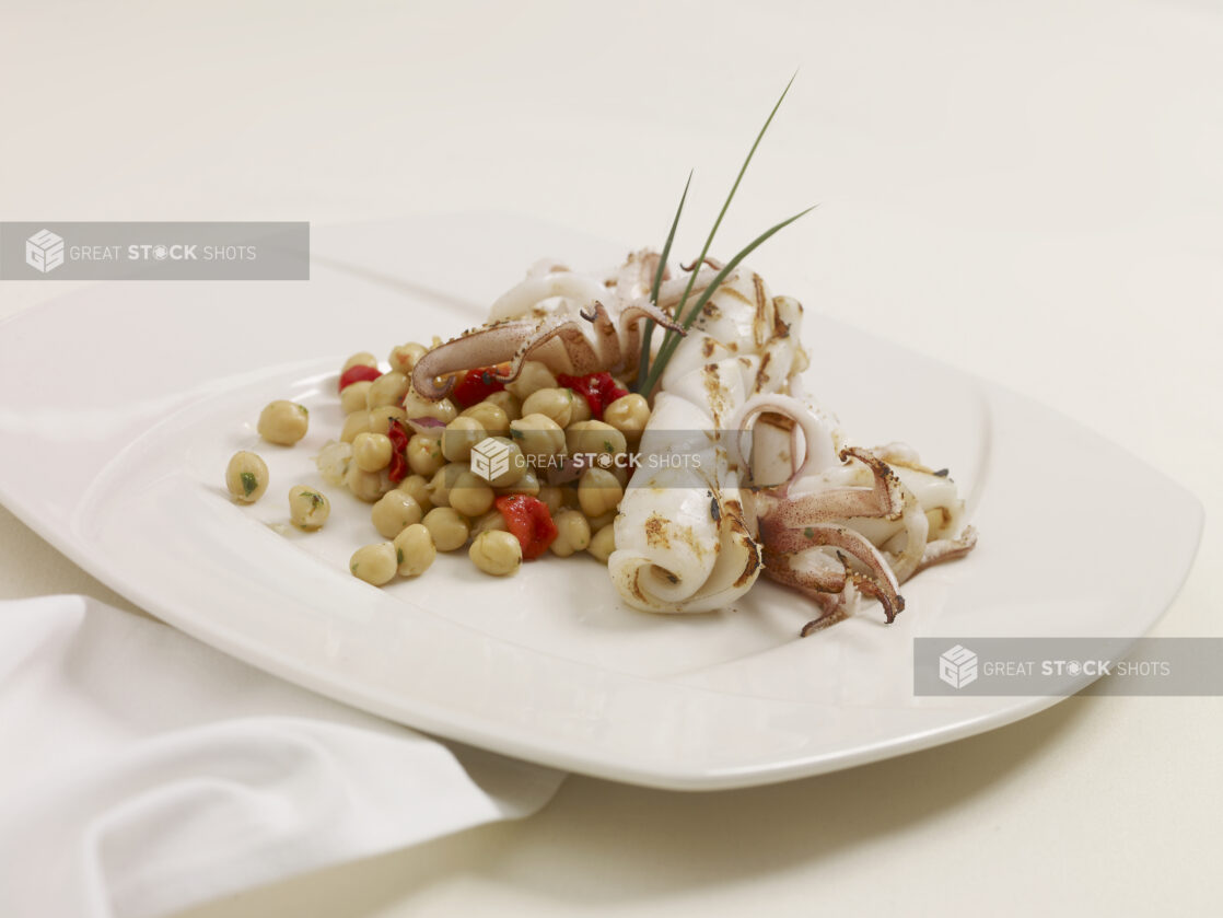 An Appetizer of Grilled Squid and Chick Peas on a White Ceramic Dish