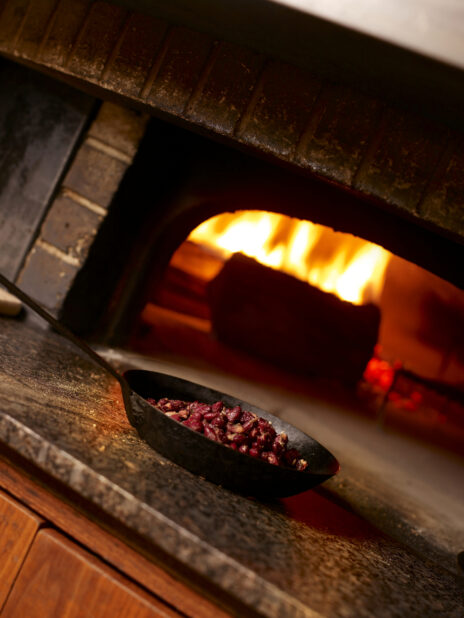 Red Kidney Beans in Cast Iron Skillet in Front of a Wood-Burning Brick Oven in a Restaurant Setting