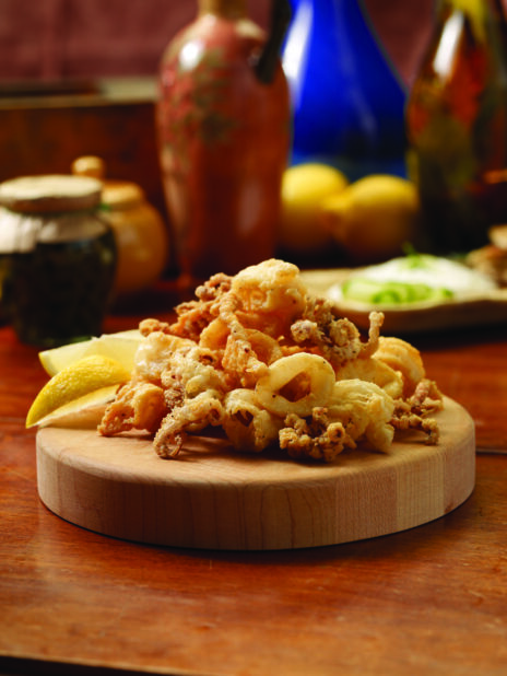 Deep Fried Calamari with Lemon Wedges on a Wooden Platter on a Wooden Table