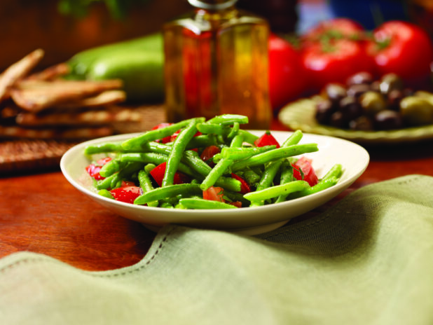 A Mediterranean Salad of Green Beans and Red Peppers in a White Ceramic Dish on a Wooden Table