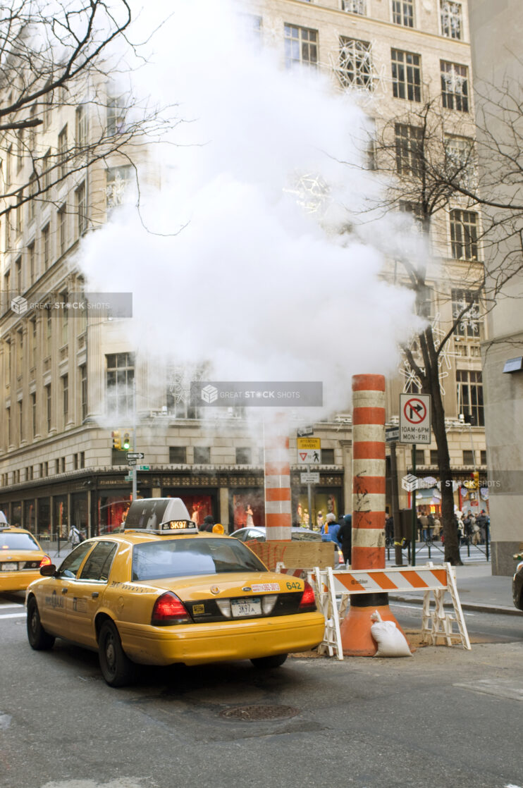 Yellow NYC Taxi Cabs Passing Large Steam Pipe Vent Stacks on the Streets of Manhattan, New York City During Winter - Variation