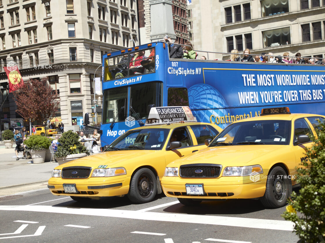 Yellow Taxi Cabs and a Blue Double Decker Sightseeing Tour Bus on a Busy Manhattan Street in New York City