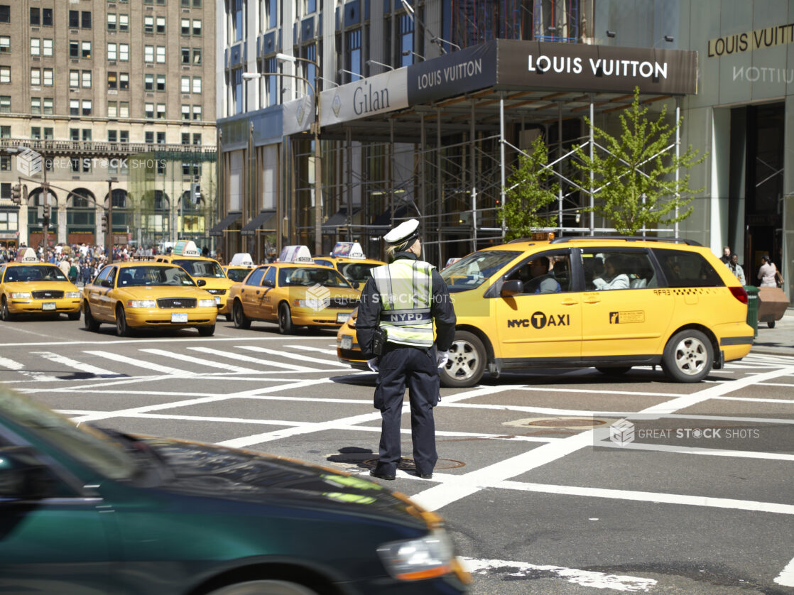 A Traffic Officer Standing in a Crosswalk Surrounded by Yellow NYC Taxi Cabs in Manhattan, New York City