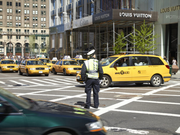 A Traffic Officer Standing in a Crosswalk Surrounded by Yellow NYC Taxi Cabs in Manhattan, New York City