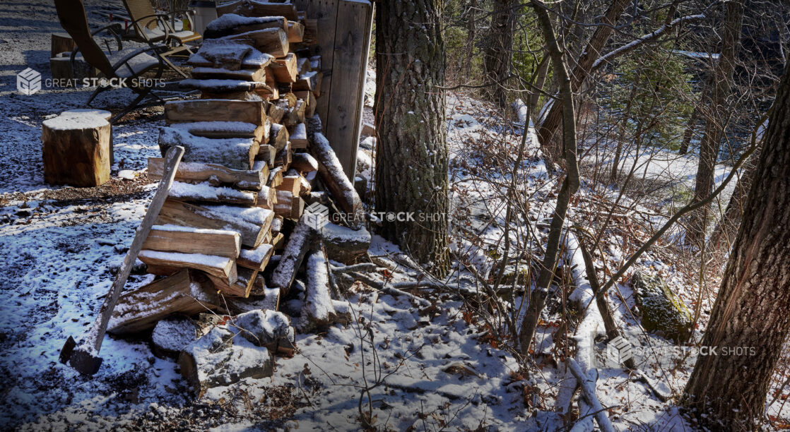 Snow Covered Fire Wood, Axe and Chopping Block on a Hill Overlooking a Lake in Cottage Country in Ontario, Canada