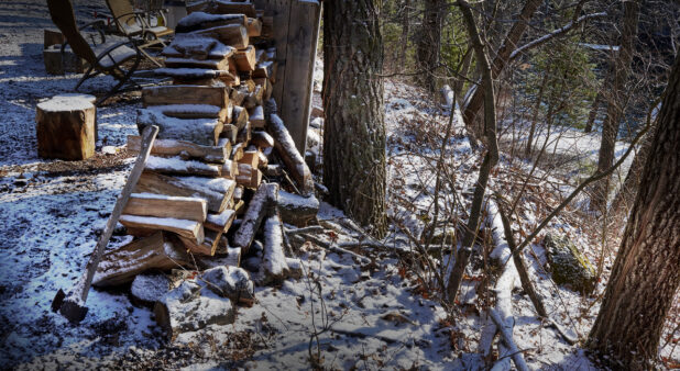 Snow Covered Fire Wood, Axe and Chopping Block on a Hill Overlooking a Lake in Cottage Country in Ontario, Canada