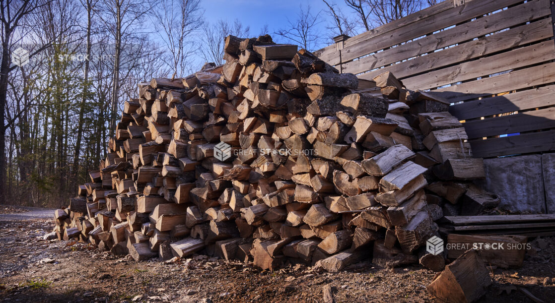 Logs for Wood-Burning Stoves Piled High for Winter Storage Against a Wooden Fence in Cottage Country, Ontario, Canada