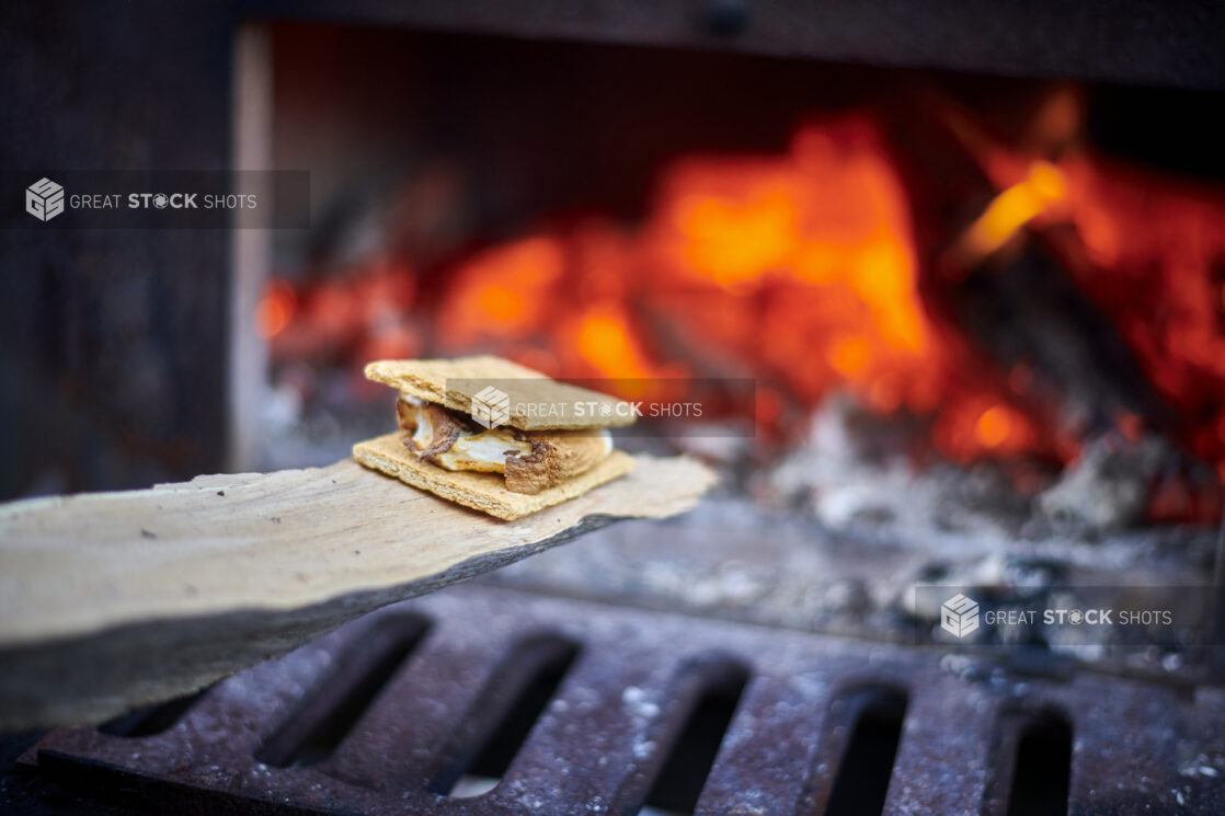 Close Up of a S'mores Treat Being Toasted Near the Open Flame of a Wood-Burning Oven in an Outdoor Setting