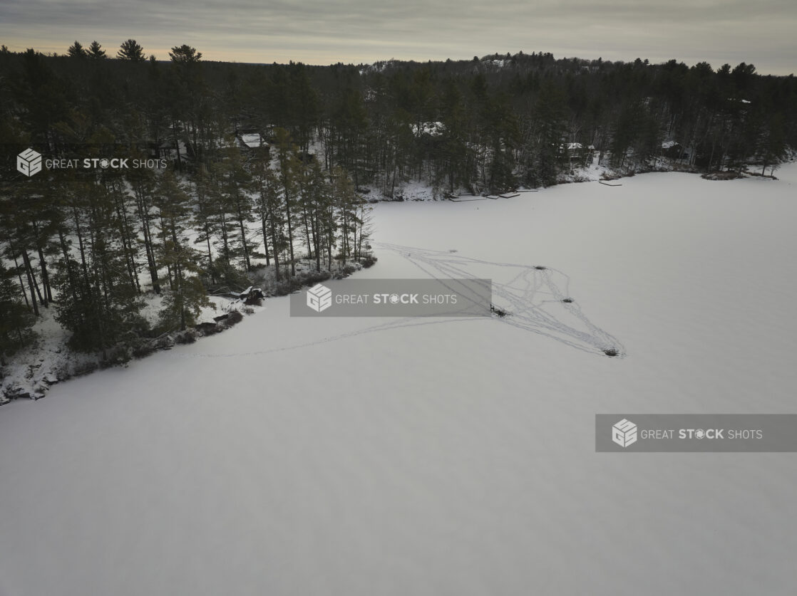 Aerial View of a Frozen Lake Covered in Snow with Ice Fishing Holes in Cottage Country in Ontario, Canada