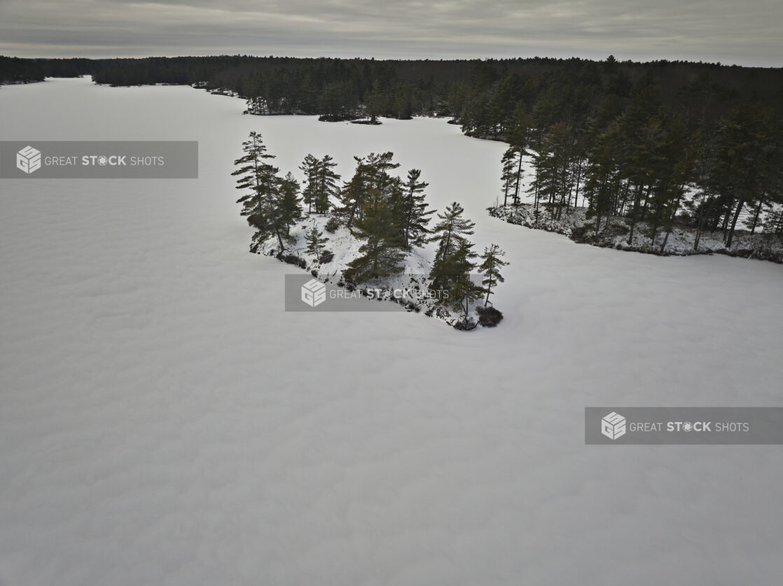 Aerial Drone View of an Island on a Frozen Lake Covered in Snow in Cottage Country in Ontario, Canada