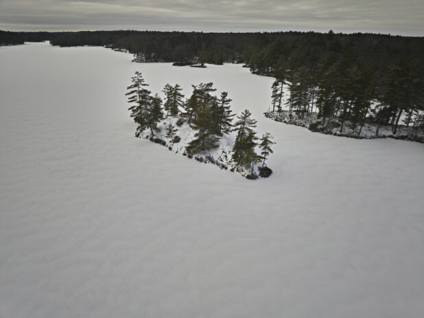 Aerial Drone View of an Island on a Frozen Lake Covered in Snow in Cottage Country in Ontario, Canada