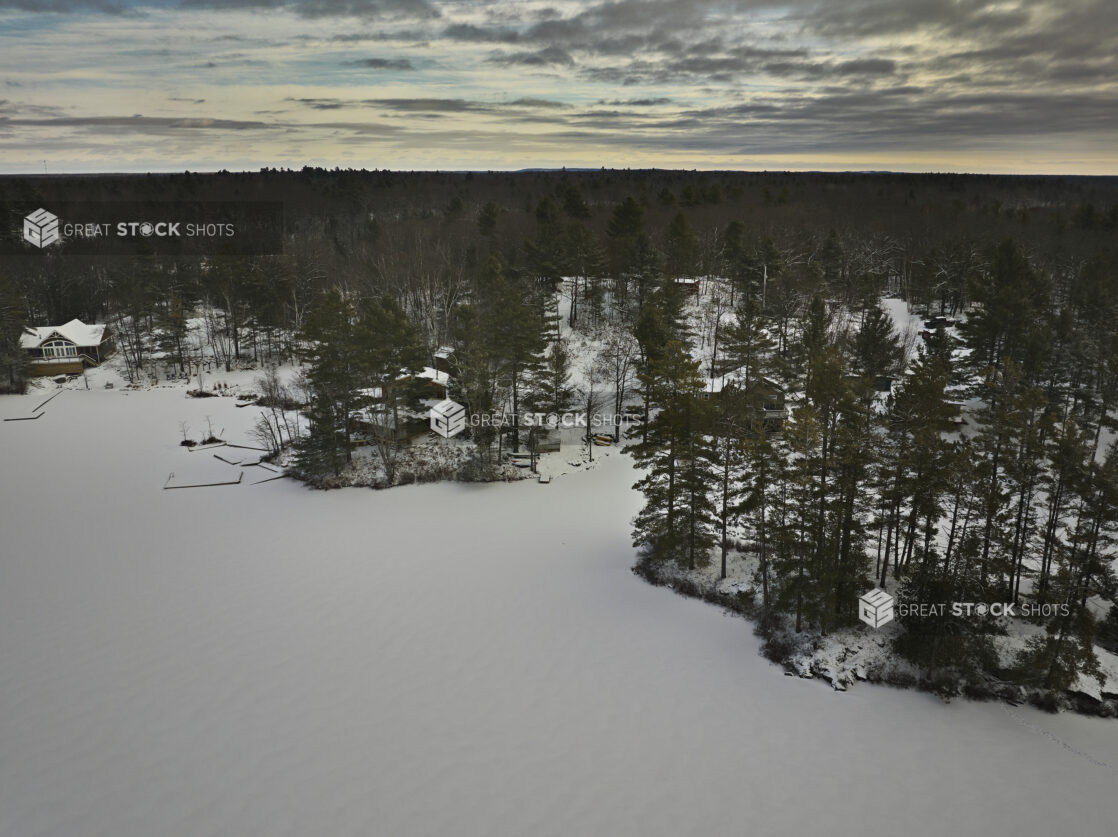 Aerial Drone View of an Evergreen Forest and Frozen Lake Covered in Snow in Cottage Country in Ontario, Canada