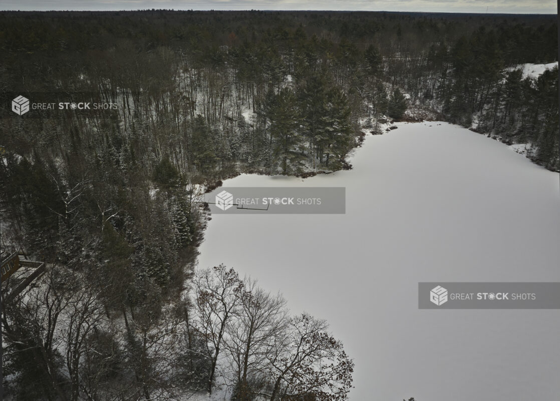 Overhead Drone View of an Evergreen Forest and Frozen Lake Covered in Snow in Cottage Country in Ontario, Canada