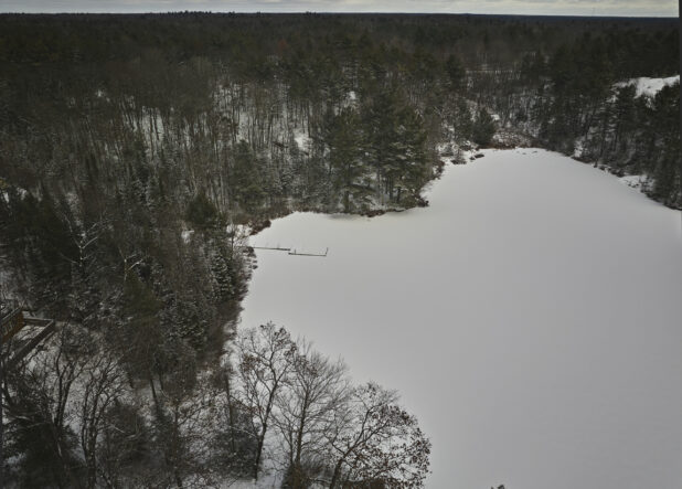 Overhead Drone View of an Evergreen Forest and Frozen Lake Covered in Snow in Cottage Country in Ontario, Canada
