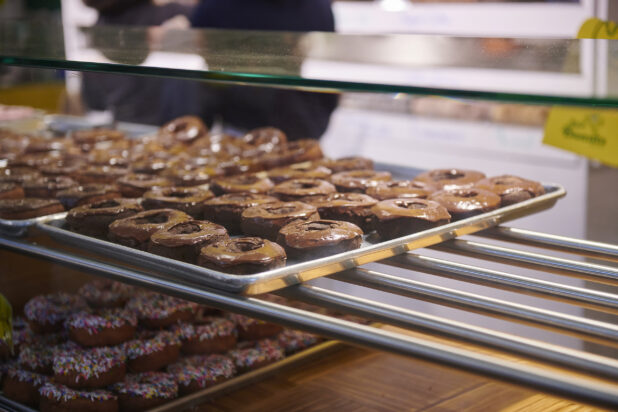 A Sheet Pan Lined With Chocolate Iced Donuts in a Donut Shop in an Indoor Market