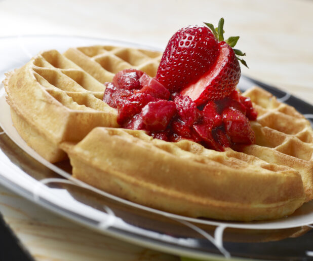 Close Up of a Plate of Waffles with Fresh Strawberries and Strawberry Sauce