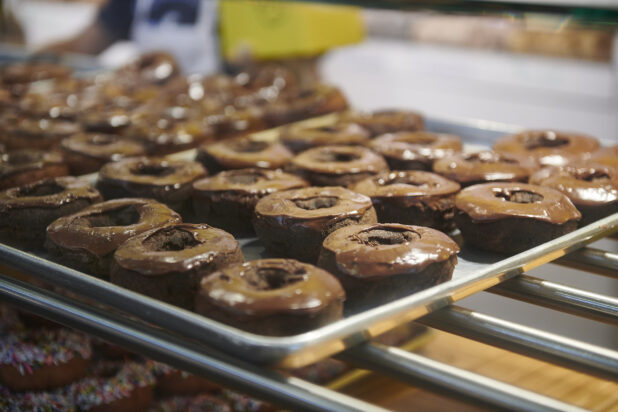 Close Up of a Sheet Pan Lined With Chocolate Iced Donuts in a Donut Shop in an Indoor Market